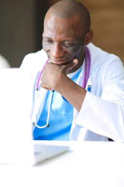 Masada dizüstü bilgisayarla çalışan genç bir Afrikalı doktor. Doktor bey. İşyeri