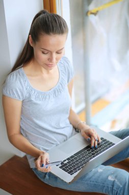 Evde bir dizüstü bilgisayar kullanan genç güzel kadın. Genç güzel kadın.