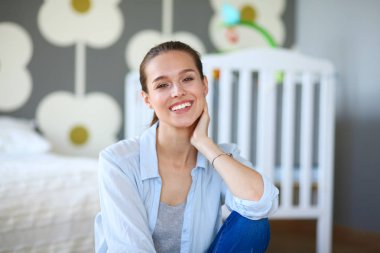 Çocuk karyolası yakın katta oturan bir genç bayan. Genç anne.