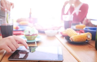 Ahşap masada otururken birlikte yemek yiyen bir grup insanın üst düzey görüntüsü. Masada yemek var. İnsanlar fast food yiyor..