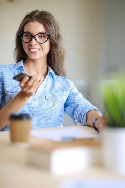 美しい若いビジネスマンの女性がオフィスの机に座って携帯電話で話しています。実業家 — ストック写真