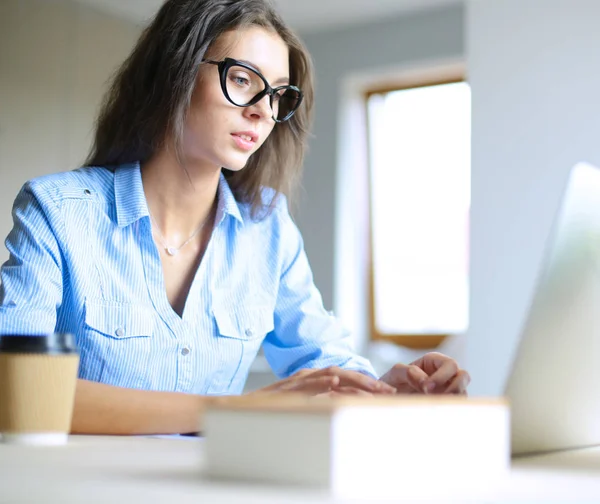 Giovane donna seduta al tavolo dell'ufficio, guardando lo schermo del computer portatile. Giovane donna — Foto Stock