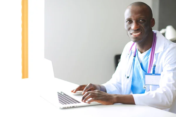 Un joven médico africano trabajando en un portátil en el escritorio. ¿Doctor? Lugar de trabajo — Foto de Stock