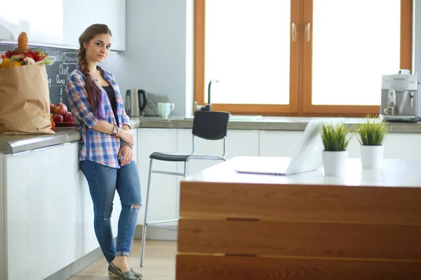 Retrato de mujer joven de pie con los brazos cruzados contra el fondo de la cocina. — Foto de Stock