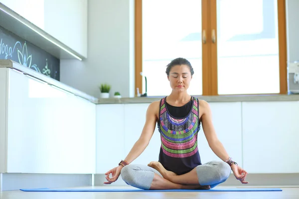 Mujer joven haciendo yoga en casa en la posición de loto. Yoga. Una mujer. Estilo de vida — Foto de Stock