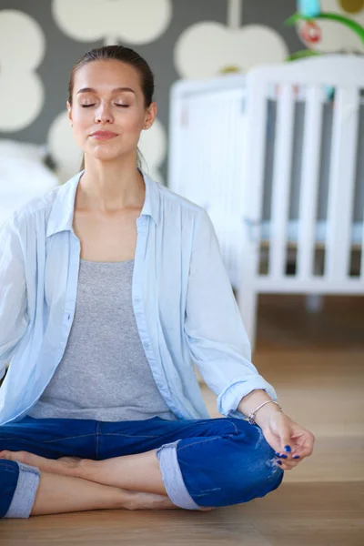 Mujer joven haciendo yoga en casa en la posición de loto. Mujer joven haciendo yoga . —  Fotos de Stock