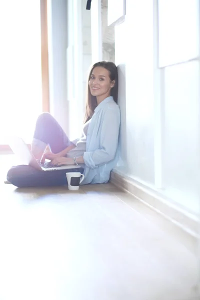 Joven hermosa mujer en casa sentada en el suelo con el ordenador portátil. Joven hermosa mujer . — Foto de Stock