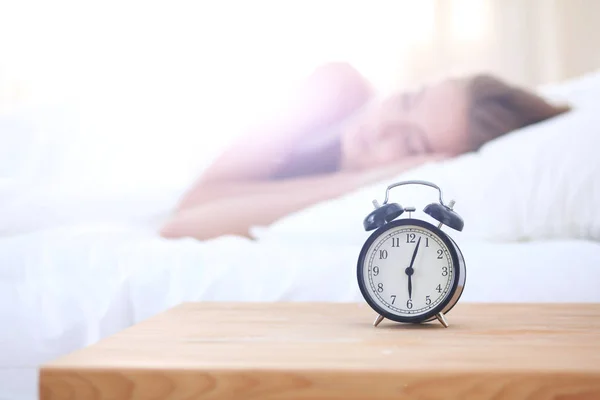 Joven mujer dormida y despertador en el dormitorio en casa. Mujer dormida joven . —  Fotos de Stock