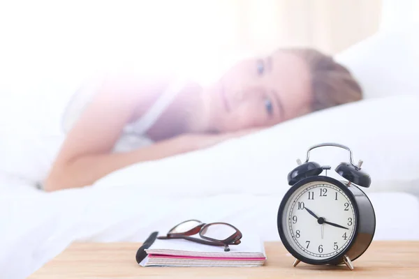 Jonge vrouw en wekker in slaapkamer thuis te slapen. Jonge slapende vrouw. — Stockfoto