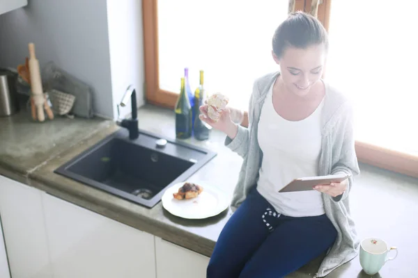 Красивая молодая женщина с помощью цифрового стола на кухне. — стоковое фото