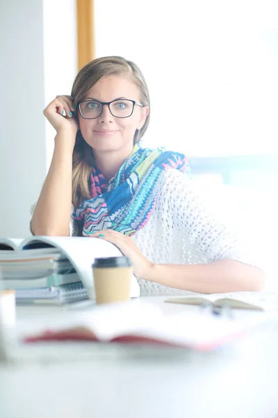 Jonge vrouw zit achter een bureau tussen de boeken. Studenten — Stockfoto