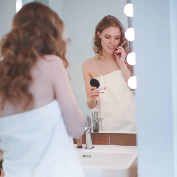 Jonge vrouw staande op badkamer met telefoon. — Stockfoto