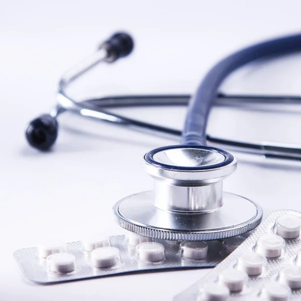 Bottles of pills and a medical stethoscope on white background — Stock Photo, Image