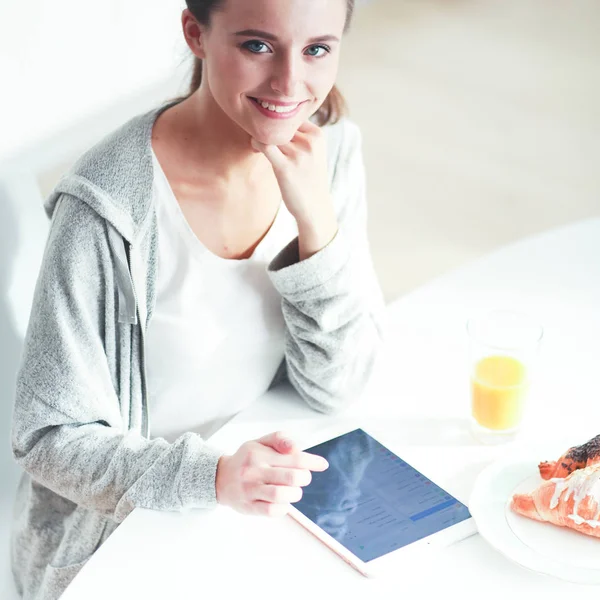 Ung kvinna med apelsinjuice och tablett i köket. — Stockfoto