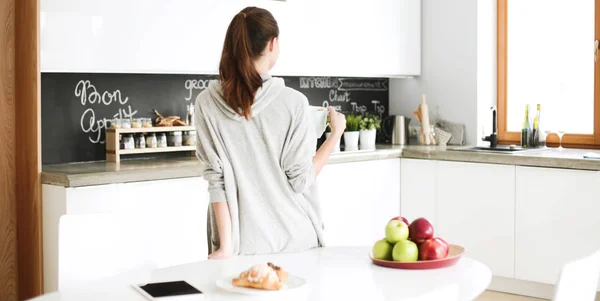 Mujer feliz bebiendo té en la cocina en casa . — Foto de Stock