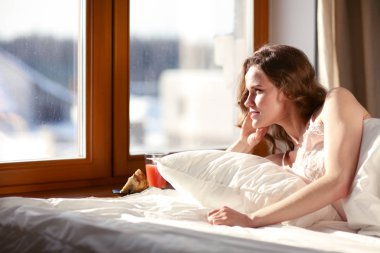 Pencere yakınındaki erken sabah yatakta yatan kadın.