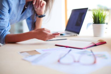 Ofis masasında oturan ve cep telefonuyla konuşan genç ve güzel bir iş kadını. İş kadını