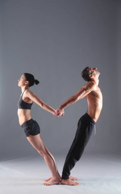 Young couple practicing acro yoga on mat in studio together. Acroyoga. Couple yoga. Partner yoga. clipart