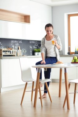 Mutfakta portakal suyu ve tableti olan genç bir kadın..