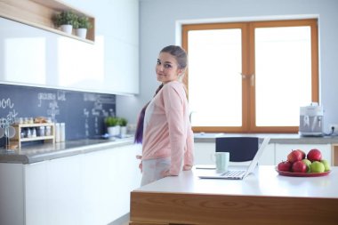 Cep telefonu ayakta modern mutfak kullanan kadın.