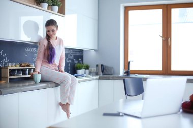 Mutfakta masada oturan genç kadın.