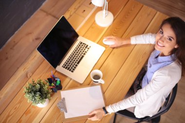 Masasında oturan ve elinde bir fincan kahveyle rahatlamış genç bir kadının portresi. İş kadını. İşyeri