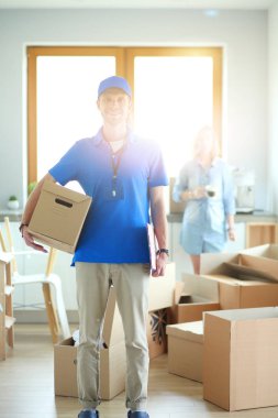 Mavi üniformalı gülümseyen kurye servis konseptine paket kutusu teslim eden teslimatçı. Mavi üniformalı gülümseyen teslimatçı.