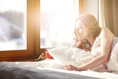 Pencere yakınındaki erken sabah yatakta yatan kadın.