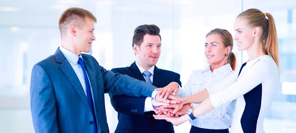 Business team joining hands together standing in office — Stock Photo, Image