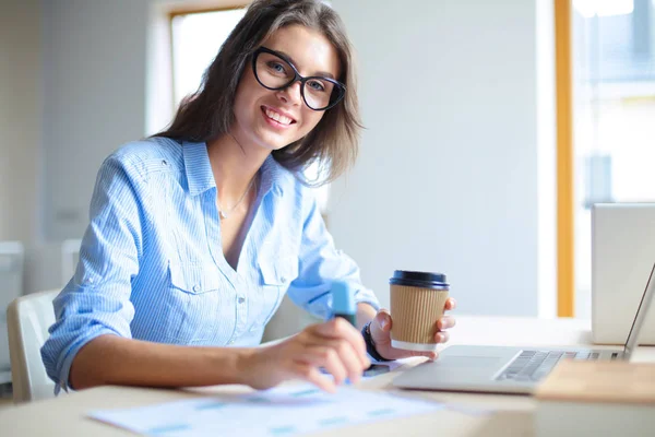 Giovane donna seduta al tavolo dell'ufficio, guardando lo schermo del computer portatile. Giovane donna — Foto Stock