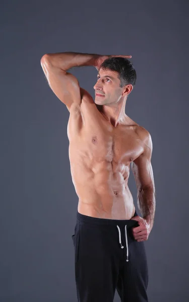 Μυώδης άνδρας. Μυώδης άνδρας σε ένα γκρίζο φόντο δείχνει τους μυς. Εκπαιδευτή γυμναστικής. Επαγγελματικής ικανότητας. Προπόνηση. Ανδρικά fitness. — Φωτογραφία Αρχείου