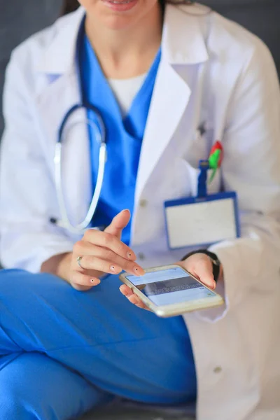 Jovem doutora sentada com seu telefone. Mulheres médicas. — Fotografia de Stock