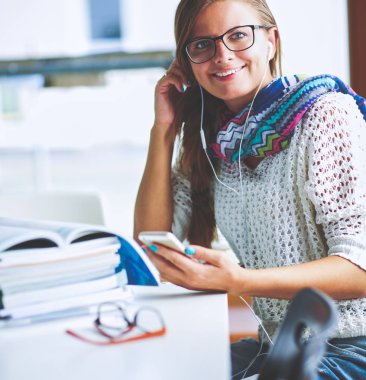 Kitapların arasında masa başında oturan genç bir kadın.