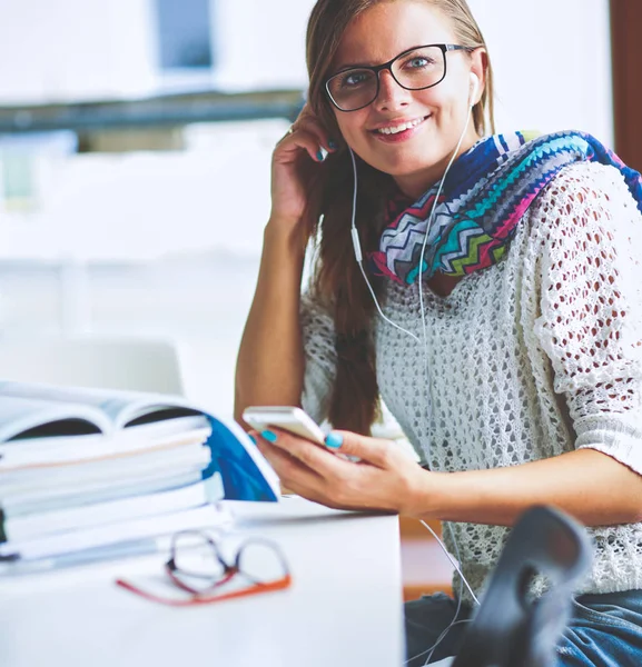 Kitapların arasında masa başında oturan genç bir kadın.