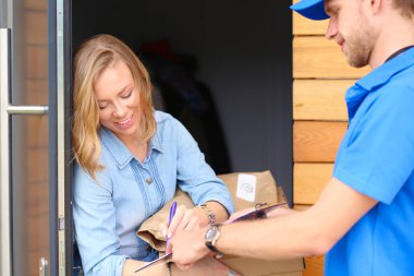 Mavi üniformalı gülümseyen kurye servis konseptine paket kutusu teslim eden teslimatçı. Mavi üniformalı gülümseyen teslimatçı.