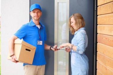 Mavi üniformalı gülümseyen kurye servis konseptine paket kutusu teslim eden teslimatçı. Mavi üniformalı gülümseyen teslimatçı.
