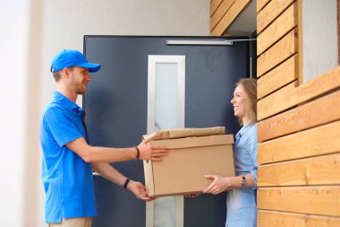 Mavi üniformalı gülümseyen kurye servis konseptine paket kutusu teslim eden teslimatçı. Mavi üniformalı gülümseyen teslimatçı.