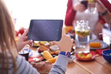 Ahşap masada otururken birlikte yemek yiyen bir grup insanın üst düzey görüntüsü. Masada yemek var. İnsanlar fast food yiyor..