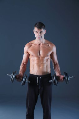 Yakışıklı kaslı adam dumbell ile çalışma dışarı. Kişisel fitness eğitmeni. Kişisel eğitim.