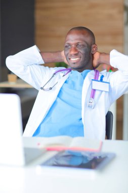 Masada dizüstü bilgisayarla çalışan genç bir Afrikalı doktor. Doktor bey. İşyeri