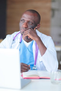 Masada dizüstü bilgisayarla çalışan genç bir Afrikalı doktor. Doktor bey. İşyeri