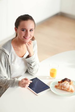 Mutfakta portakal suyu ve tableti olan genç bir kadın..