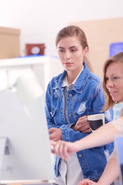 Masanın yanında duran iki genç kadın enstrüman, plan ve dizüstü bilgisayarla.