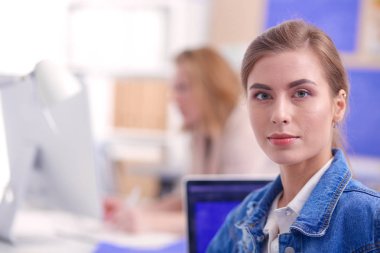 İki genç kadın masada enstrümanlar, planlar ve dizüstü bilgisayarlarla oturuyor..