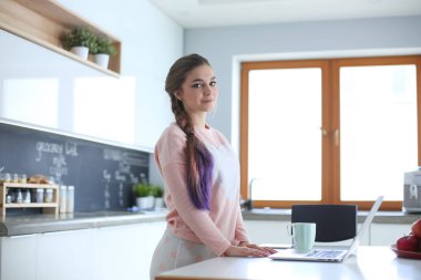 Cep telefonu ayakta modern mutfak kullanan kadın.