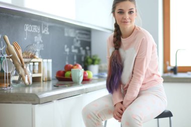 Mutfakta masada oturan genç kadın.