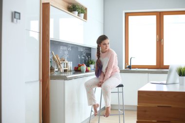 Mutfakta masada oturan genç kadın.