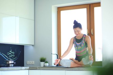 Lotus pozisyonunda mutfak masasında oturan genç güzel kadın. Kadın. Yoga