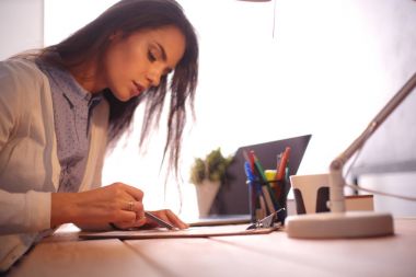 Masada oturan genç bir bayan. İş kadınıyım. Çizim. Öğrenci. İş yeri. Masa.