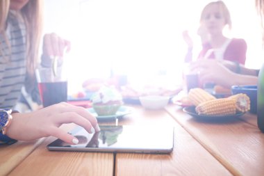 Ahşap masada otururken birlikte yemek yiyen bir grup insanın üst düzey görüntüsü. Masada yemek var. İnsanlar fast food yiyor..